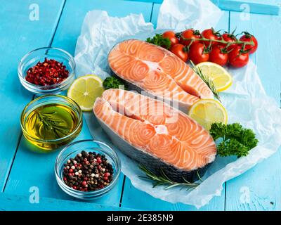due trote crude di pesce bistecca, salmone e spezie su sfondo di legno blu Foto Stock
