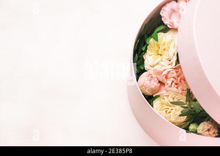 Una disposizione elegante e delicata dei fiori in una scatola rotonda cappello sullo sfondo rosa con spazio per la copia. Confezione regalo per l'8 marzo, Giornata internazionale della donna Foto Stock