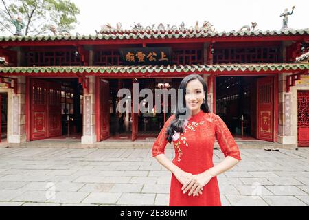 Ritratto di felice giovane bella donna asiatica in pizzo rosso vestitevi in piedi all'intrattenimento del tempio Foto Stock