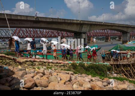 I lavoratori scaricano concime una nave di curgo sulla riva del fiume meghna ad Ashuganj, Brahmanbaria, Bangladesh. Foto Stock