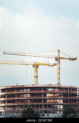 Profilati in acciaio di un edificio in costruzione, con due gru a torre sulla parte superiore. Strutture in cemento armato Foto Stock