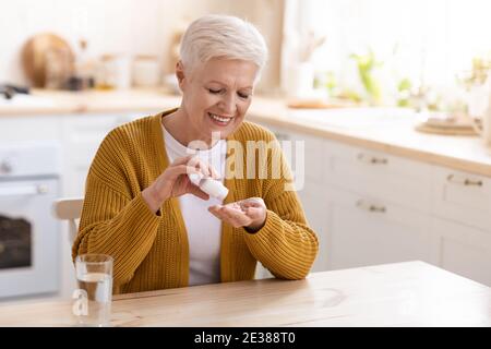 Anziana donna sana con integratori, cucina interna Foto Stock