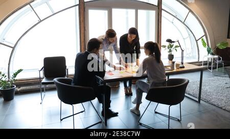Dipendenti diversi che lavorano con documenti di progetto, utilizzando carte adesive Foto Stock