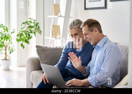 Felice coppia di nonni vecchi che ondeggiano mano facendo una videochiamata online su un computer portatile. Foto Stock