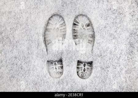 due stampe di scarpe affiancate in neve fresca sul marciapiede. Foto Stock