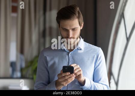 Primo piano dirigente uomo d'affari serio guardando lo schermo del telefono Foto Stock