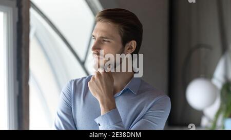 Primo piano pensieroso uomo d'affari sognante che tocca il mento, meditando strategia Foto Stock