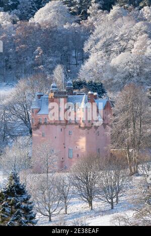 Craigievar Castello circondato da alberi di bosco in un inverno innevato Paesaggio in Scozia Foto Stock