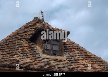Tetto in tegole in ceramica rumena con licheni e vecchia antenna televisiva Foto Stock