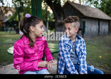 Felici i piccoli amici che parlano mentre si siede nel parco, trascorrendo del tempo in bella natura. Messa a fuoco selettiva. Foto Stock