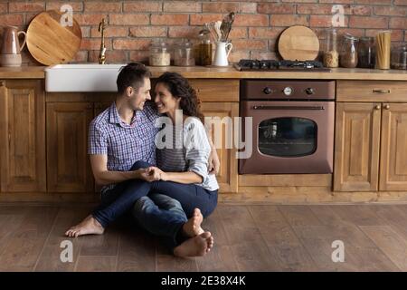 Felice coppia millenaria rilassarsi abbracciando in propria cucina Foto Stock