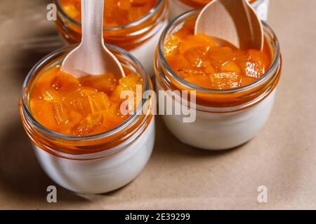 Frullato di panna montata e persimmon in un vaso di vetro. Cucchiai in legno in vasi. Foto Stock