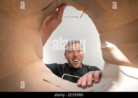 Felice uomo sorridente che guarda in borsa di carta con generi alimentari dal negozio. Foto Stock