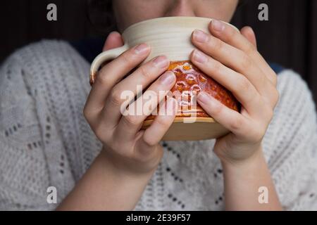 Giovane donna con tazza di tè. Autunno o inverno Moody fine settimana. Giorno pigro, quarantena, soggiorno a casa, scena accogliente, hygge concetto. Foto Stock