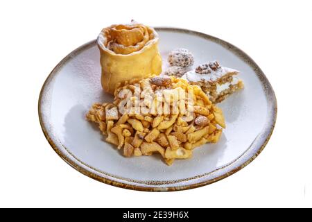 Dessert di dolci freschi, chak-chak, cosparso di zucchero in polvere in un piatto su uno sfondo bianco isolato. Piatto tradizionale nazionale tatar. Foto Stock