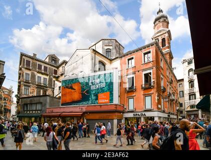 I turisti affollano campo San Bartolomio, una piccola piazza piena di negozi e caffè vicino al Ponte di Rialto nel centro storico di Venezia Foto Stock