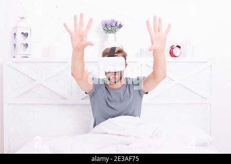 La migliore esperienza di VR. Bel ragazzo indossa le cuffie VR a letto. Uomo caucasico utilizzando occhiali VR in camera da letto. Il rendering di coinvolgente in VR. Foto Stock