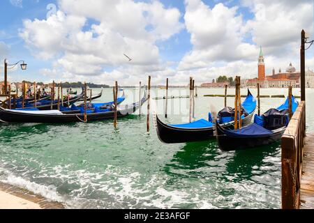 Gondole lungo il Canal Grande con la Riva di Schiavoni e la Chiesa e l'isola di San Giorgio maggiore visibili in lontananza a Venezia. Foto Stock
