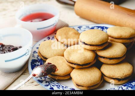 Biscotti fatti in casa con marmellata o confettura di prugne di frutta in un piatto - primo piano vista frontale cotta cibi dolci tradizionali ricetta - concetto di alimentazione sana Foto Stock