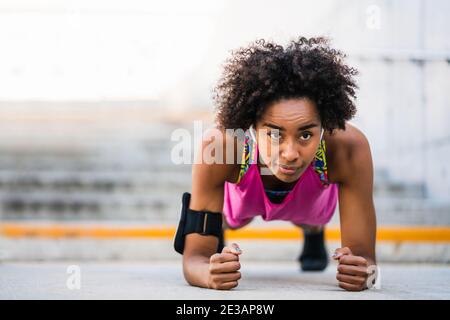 Donna afro atleta che fa pushup all'aperto. Foto Stock