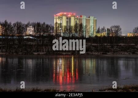 Alto edificio sulla riva del fiume Uvod e il suo riflesso sulla superficie ghiacciata dello specchio, Ivanovo, Russia. Foto Stock