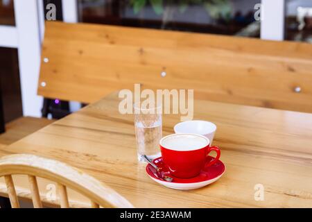 Tazze da caffè sporche, cappuccino e un bicchiere d'acqua si trovano su un tavolo di legno. Pausa caffè. Deliziatevi con gusto e aroma. Foto Stock