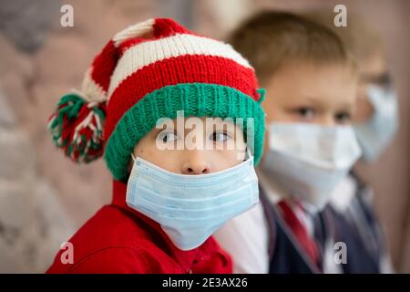 24 dicembre 2020. Bielorussia, la città di Gomil. Vacanze di Natale in città. Un ragazzo che indossa un cappello di babbo natale e una maschera medica al holi di Natale Foto Stock