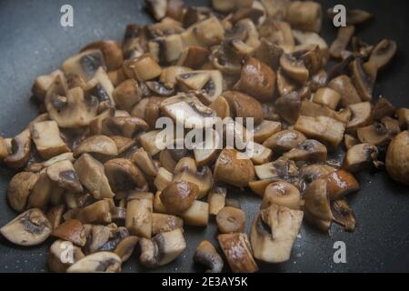 Vista ravvicinata delle fette saltate dei funghi comuni (Agaricus bisporus) cottura in padella Foto Stock