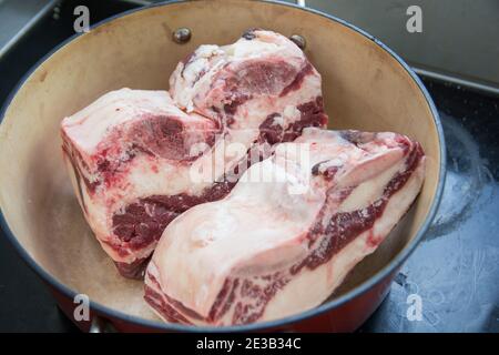Scongelamento di due fette di carne di costolette corte in un pentolino rosso Foto Stock