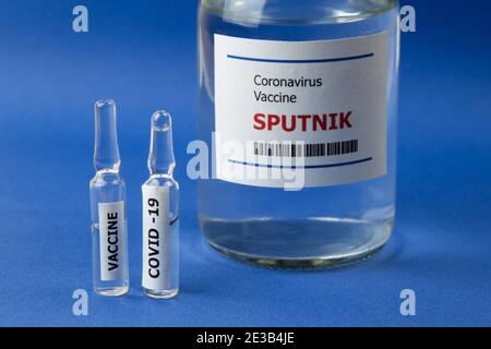 Krasnodar, Russia - 12 gennaio 2021: Due fiale e una bottiglia di vaccino Sputnik da Covid-19 su sfondo blu Foto Stock