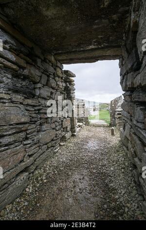 Vista della via d'ingresso in pietra nell'edificio principale del Broch of Gurness, un villaggio di criciola dell'era del ferro sulla costa nord-est di Orkney, Scozia Foto Stock