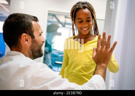 Felice bambina e pediatra che fanno alto cinque dopo medico check-up in ospedale Foto Stock