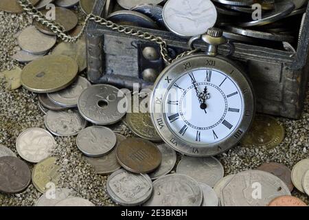 Vecchia tasca orologio sulla sabbia con monete. Moneta da cruscotto criptovaluta, fondo in sughero, spazio vuoto Foto Stock