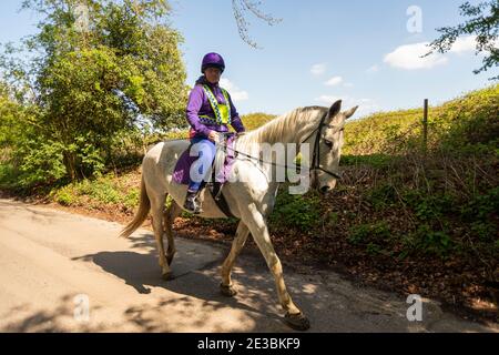 Una cavaliere femminile che si allacca su una corsia di campagna Foto Stock