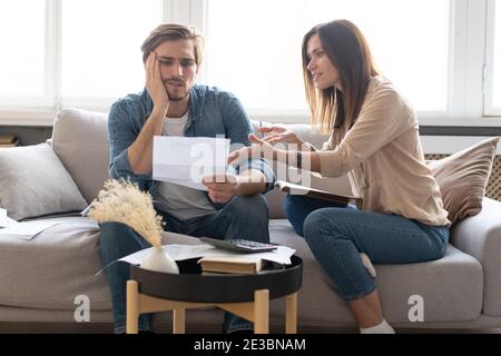 Foto di giovane coppia allegra che analizza le proprie finanze con documenti Foto Stock