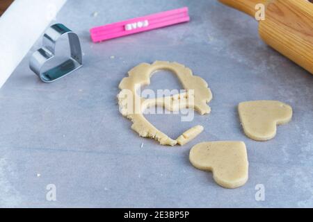 Processo di produzione di biscotti a forma di cuore. Concetto di pasticceria romantica. Foto Stock