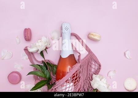 Composizione primaverile con spumante rosato, peonie bianche e macaron Foto Stock