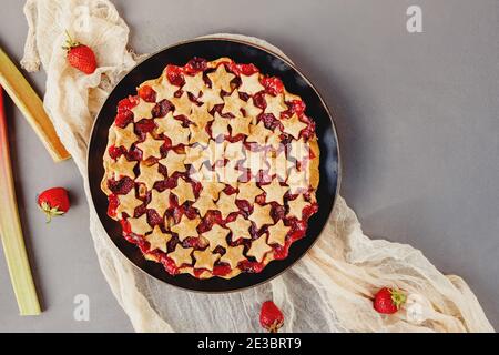 Torta di fragole e rabarbaro decorata con stelle sul tavolo grigio Foto Stock