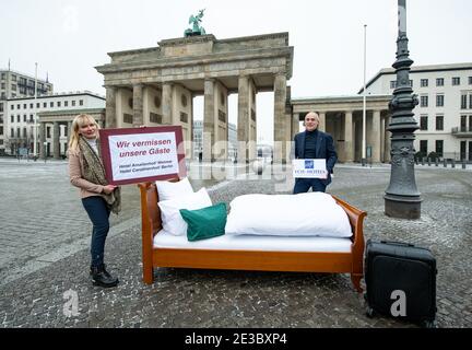 18 gennaio 2021, Berlino: Claudia Wießner (l), amministratore delegato degli alberghi Amalienhof a Weimar e Carolinenhof a Berlino, si trova insieme ad Axel Möller, amministratore delegato della cooperazione alberghiera VCH-Hotels, su un letto di fronte alla porta di Brandeburgo. Sotto il motto "We miss our guests", il letto è allestito con breve preavviso in varie località della Germania per scattare foto. Il letto è già stato allestito di fronte al monumento Goethe-Schiller a Weimar, e altre località sono da seguire. I governi federale e statale discuteranno di misure più severe a Corona per il 19.01.2021. Foto Stock