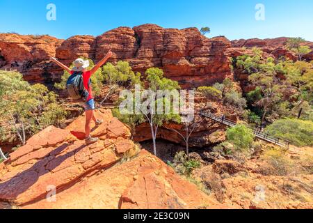 Vista panoramica della donna al Kings Canyon Rim Walk con passerella sul Garden of Eden, Watarrka National Park, Australia. Ospite femminile godendo Foto Stock