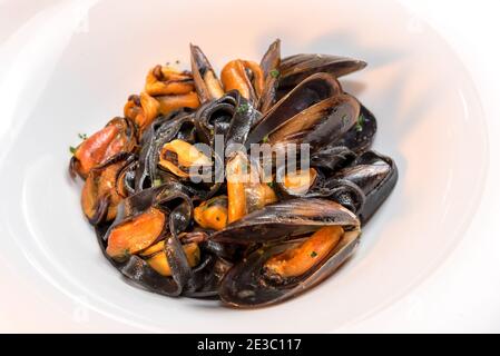 inchiostro di calamari di pasta nera con cozze - tagliatelle italiane al nero di seppia - primo piano in un piatto bianco Foto Stock