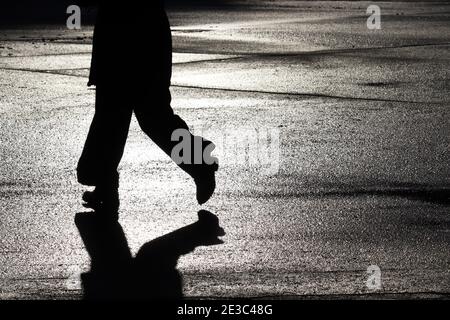 Silhouette nera e ombra di donna che cammina su una strada. Concetto di solitudine, pedone running girl, drammatica vita umana Foto Stock