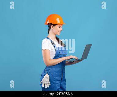 Beautiful Young Female Maintenance Worker Using laptop, Ordering Construction Materials Online Foto Stock