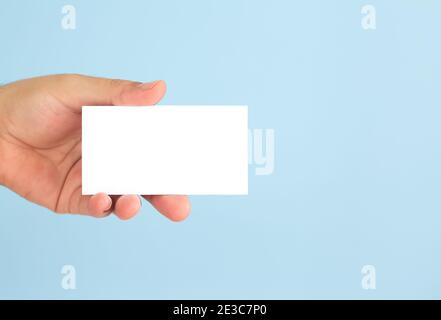 Mano di uomo d'affari che tiene il biglietto da visita vuoto su sfondo azzurro chiaro. Modello per il tuo design Foto Stock