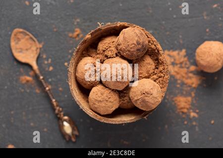 tartufi di cioccolato fondente polvere di cacao in una ciotola di conchiglia di cocco, vista dall'alto Foto Stock