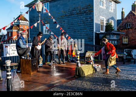 A Local Woman dà denaro a UN gruppo di artisti di strada che si esibiscono in High Street, Lewes, East Sussex, UK Foto Stock