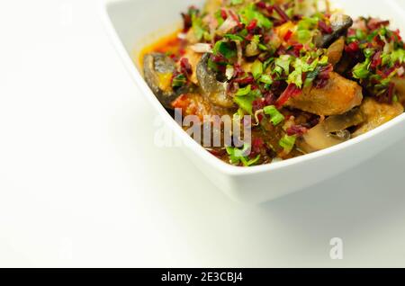 Un stufato di carne, patate, funghi e un mix di peperoni serviti in una ciotola bianca, pasto delizioso Foto Stock