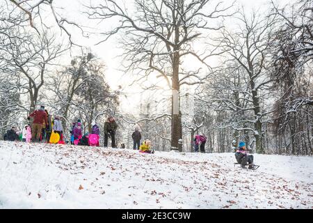 felici i bambini e i loro genitori che dormono nel parco invernale. Divertimento di Natale durante le vacanze Foto Stock