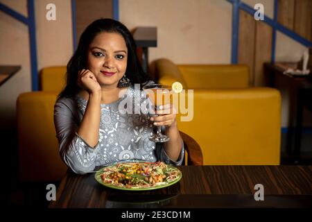 Ritratto di una bella donna che mangia cibo delizioso in un ristorante. Foto Stock
