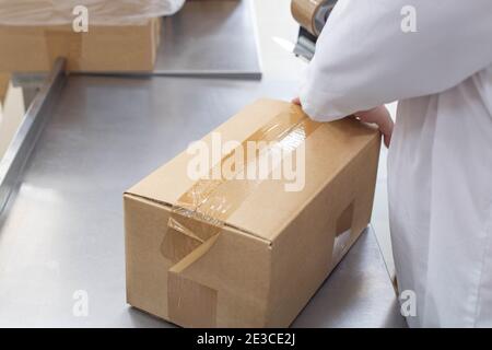 worker confeziona scatole con prodotti in una fabbrica, industria. Processo, trasporto Foto Stock